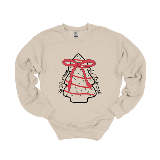 Christmas tree little Debbie graphic on a sand soft lined crewneck. Tis the season is written along the sides of the graphic for the perfect holiday look. Matching option for the whole family. Available in crewneck for adults and long sleeve for kids. 